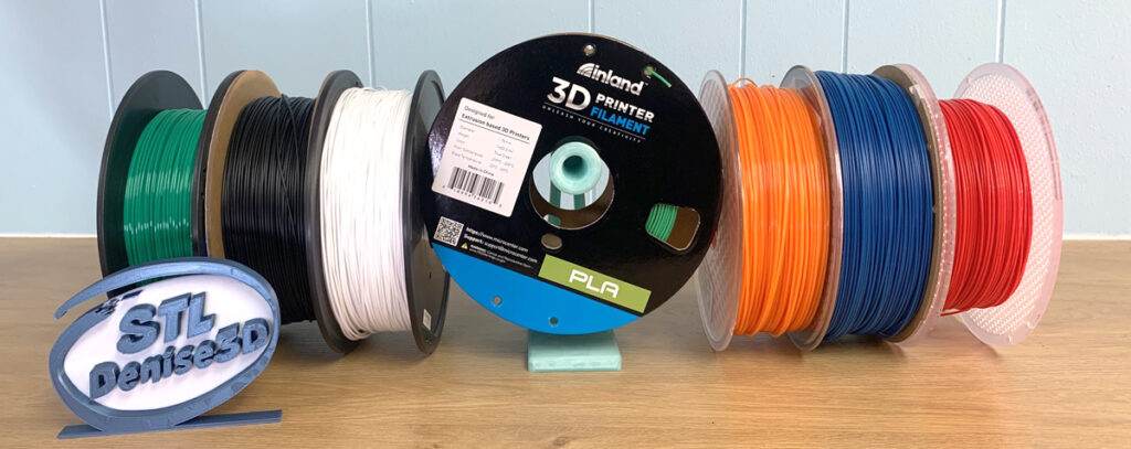 spools of PLA filament for 3d printing in green, black, white, orange, blue and red.